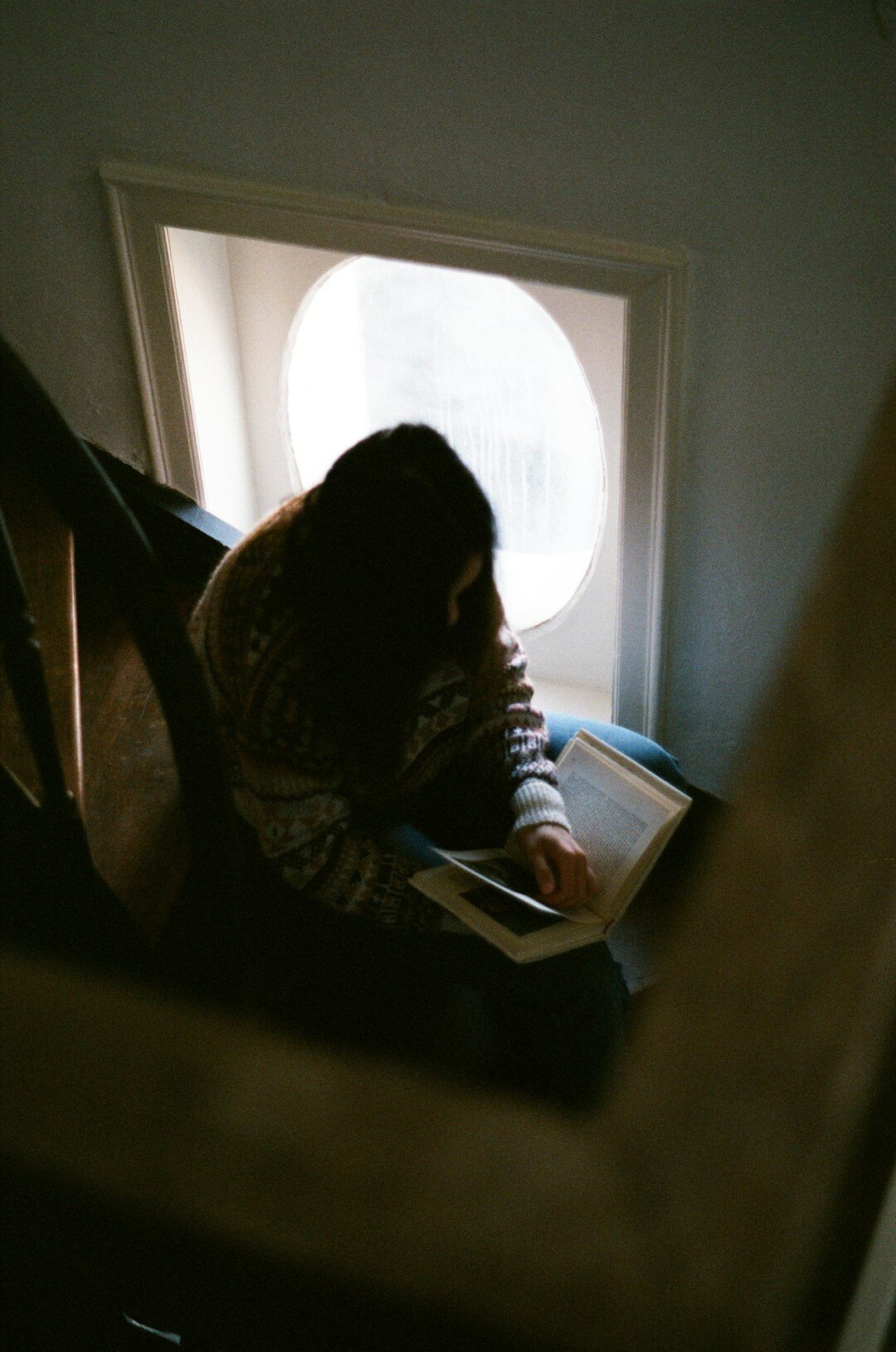 woman reading book by window